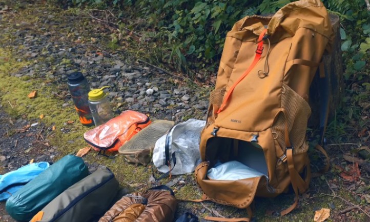A backpack, sleeping bag, and camping gear arranged neatly on the ground, ready for an outdoor adventure