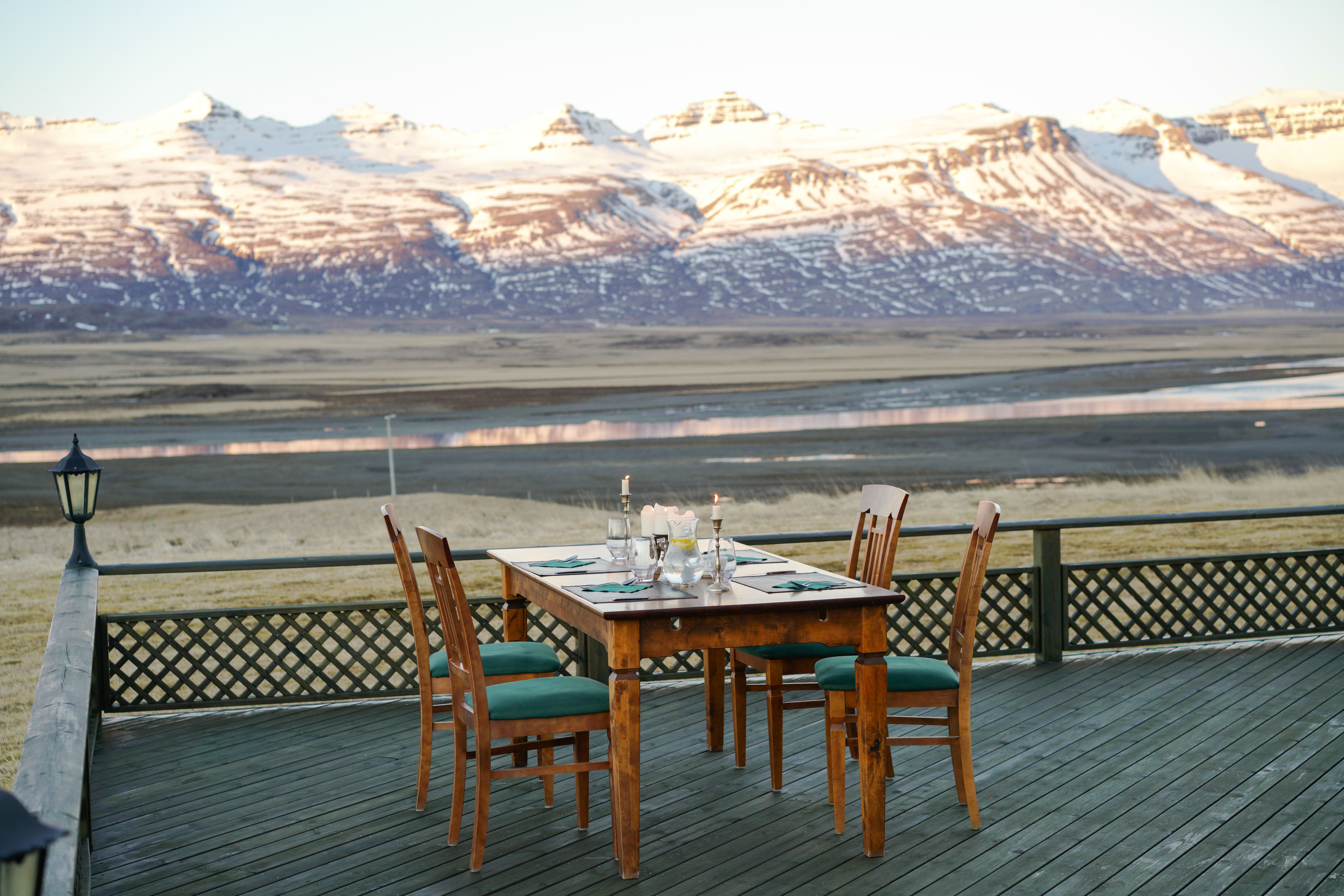 Outdoor dining table set on a wooden deck with snow-capped mountain views